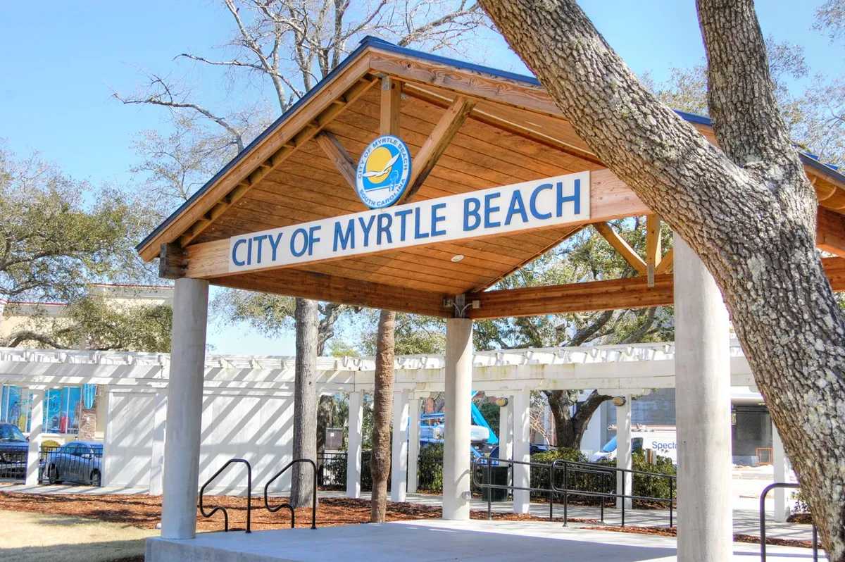 The welcoming 'City of Myrtle Beach' sign sits beside a charming wooden pavilion surrounded by greenery. This location is a hub for community events and a starting point for exploring local attractions.