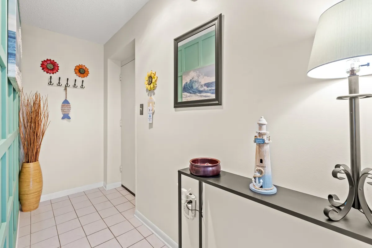 A colorful, inviting elevator lobby area adorned with cheerful wall decor, a lighthouse figurine, and decorative elements. The space is bright and welcoming, suggesting easy access to upper floors and a warm first impression for residents and guests alike.