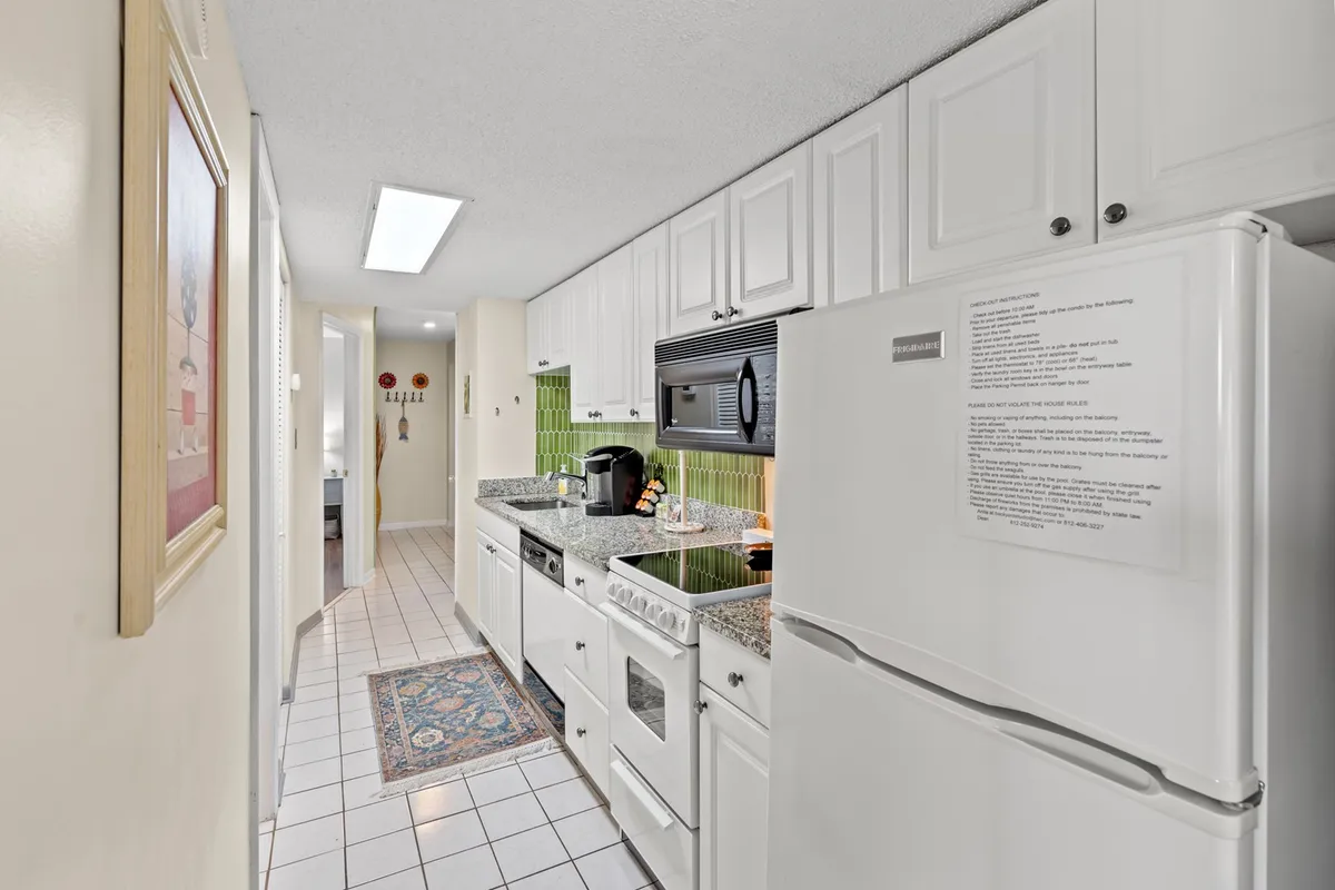A welcoming kitchen scene showcasing granite countertops, white cabinetry, a green backsplash, and quality appliances. The layout offers both functionality and style, creating a space where cooking and socializing come naturally.